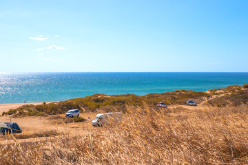 tourist camping with trailers and tents on the seashore on a sunny autumn day. Travel and tourism