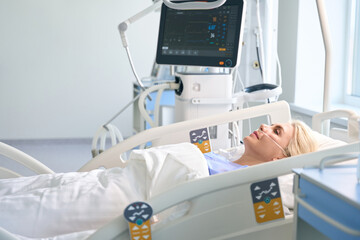 Female blonde after surgery lies in room with modern equipment