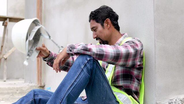 4K Asian foreman frustrated and hopeless worried unemployed or financial crisis lose a job, labor worker man relaxing after lunch break sitting on construction site, middle-age contractor male tried