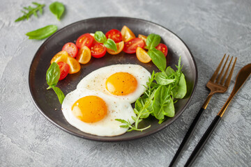 Fried eggs and Caprese salad with tomatoes, mozzarella cheese and basil leaves in a plate.