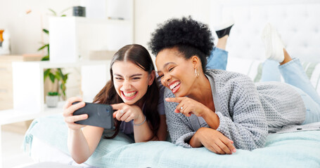 Phone, happy and girl friends on a bed for relaxing, bonding and watching a funny, comic or comedy video. Smile, laugh and young women scroll on social media, mobile app or the internet in bedroom.