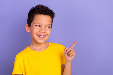 Photo portrait of cute young schoolboy finger point look empty space wear yellow clothes isolated on purple color background