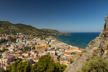 View of Cefalù, the city, the cathedral and its castle. Panorama seen from above of the whole landscape. Rough sea during sunset. The most beautiful places in Sicily. Excellent tourist destination.