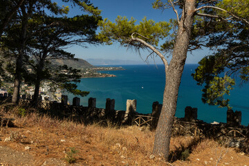 View of Cefalù, the city, the cathedral and its castle. Panorama seen from above of the whole landscape. Rough sea during sunset. The most beautiful places in Sicily. Excellent tourist destination.