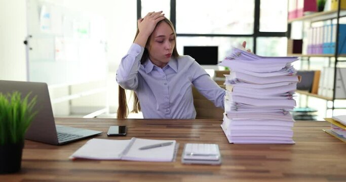 Upset tired woman looking at large pile of work documents. Overtime and overwork