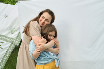 Under the summer sky, a joyful reunion occurs between a mother and her daughter amidst washed clothes. impact of familial bonds in addressing the psychological needs of children.