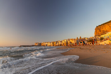 View of Cefalù, the city, the cathedral and its castle. Panorama seen from above of the whole landscape. Rough sea during sunset. The most beautiful places in Sicily. Excellent tourist destination. - obrazy, fototapety, plakaty