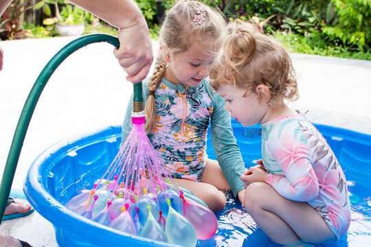 Kids playing in a kiddie pool with water balloons. Summer activities for kids. Backyard fun 