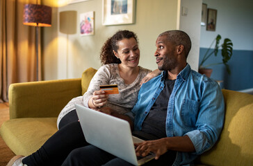 Mixed couple online shopping together on the laptop at home