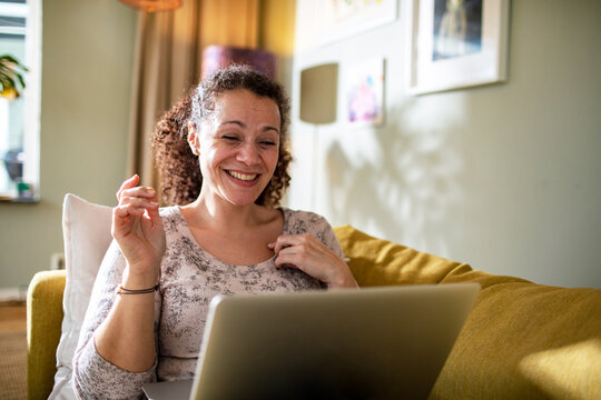 Young mixed woman having a video call on her laptop at home