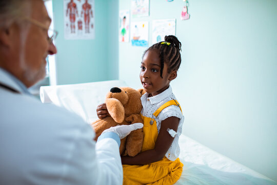 Young African American girl talking to her pediatrician after getting a vaccine shot in the clinic