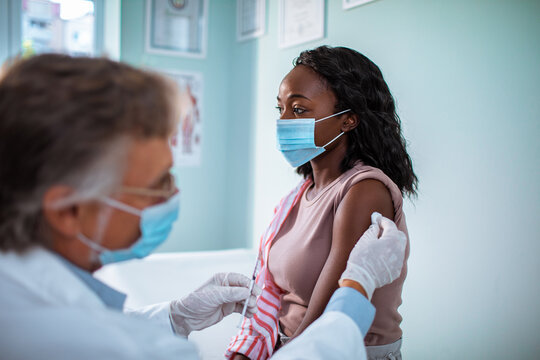 Young African American woman is about to be vaccinated by a doctor at the hospital