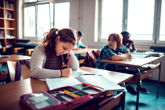 Young girl writing notes in a elementary school classroom