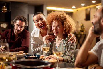 Diverse age group of friends having lunch and wine together in the kitchen at home