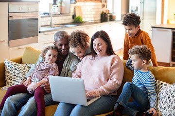 Young mixed family using a laptop together on the couch at home