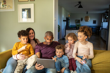 Young mixed family using the tablet together on the couch at home
