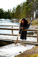 Young woman feeding duck by frozen lake
