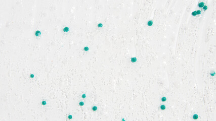 Transparent gel with blue granules smeared serum on a white background