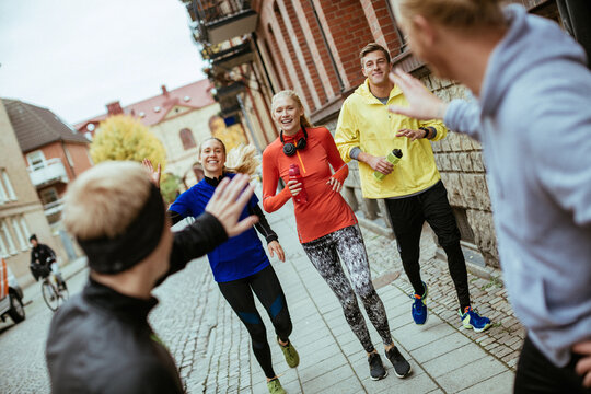 Young and diverse group of people greeting their friends on street to go run together in the city