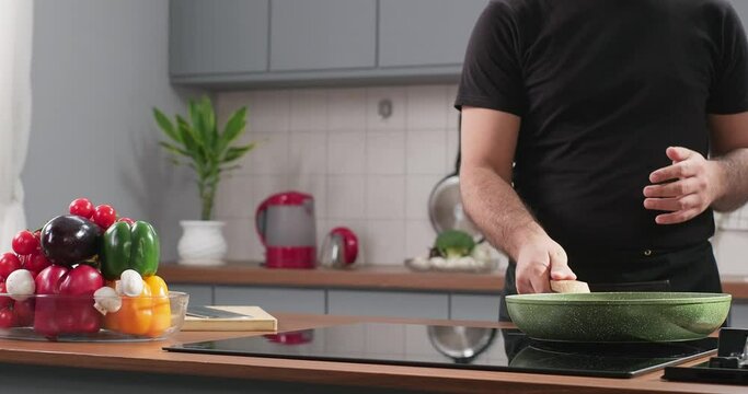 Chef puts frying pan on induction stove. Starting to cook vegetarian food at modern home cuisine. Preparing meal in the kitchen, cooking blog. Slow motion