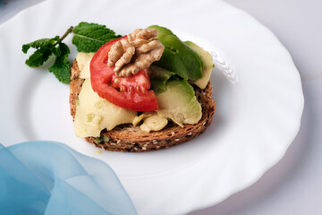 Toasted bread with avocado paste and fresh tomato. The avocado is spread on the bread. Healthy food concept, vegan, vegetarian