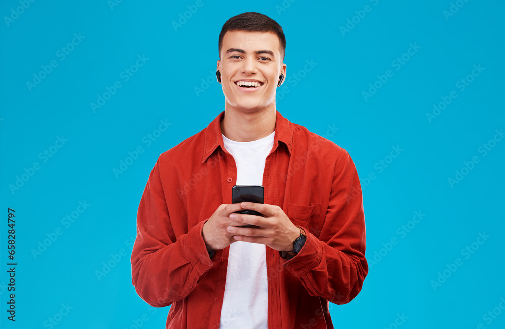 Poster man, earphones and smile with phone for communication in portrait, studio and happy by blue backgrou