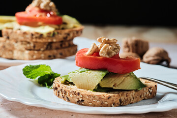 Close-up of toasted bread with avocado paste and fresh tomato. The avocado is spread on the bread. Healthy food concept, vegan, vegetarian
