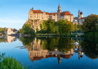 Naklejka na ściany i meble Sigmaringen castle is a historic monument and landmark in southern Germany on a rock in old town centre. Late summer evening panorma with reflection in river Danuve and water fowl. Tourist attraction.