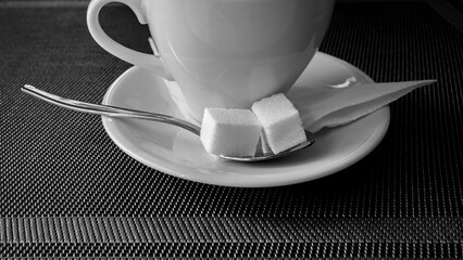 Cup of coffee spoon with sugar on a gray background.