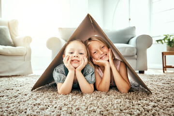 Portrait, children and cardboard for insurance with girl sisters on the floor of the living room at...