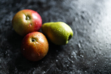Apples, pears, green and purple grapes lie on a dark background. Organic fruit close-up. Fruits on a black background. Wet washed fruits on a black marble table