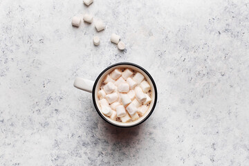 Mug with hot chocolate or cocoa with marshmallow on white concrete table. Overhead view, copy...