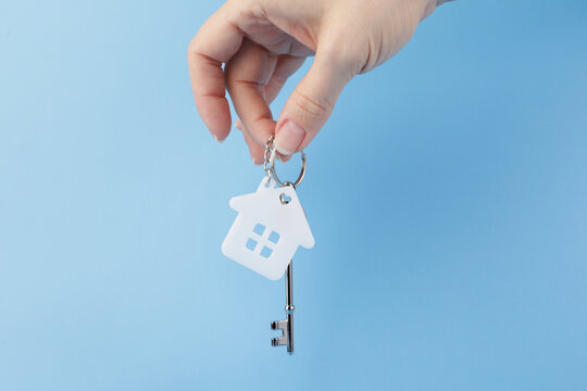 renting an apartment, buying and selling property,  house key in hand on a blue background, copy space, credit and mortgage, real estate services
