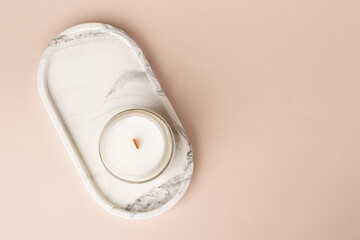 Candle on a marble stand on a beige background, top view, copy space, Spa retreat decoration