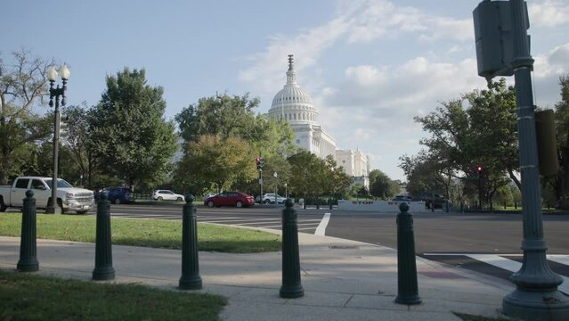 Slow motion view of Capital building holding congress house representatives and senators in Washington DC, including pedestrians, streets, and traffic during a bright, fall afternoon