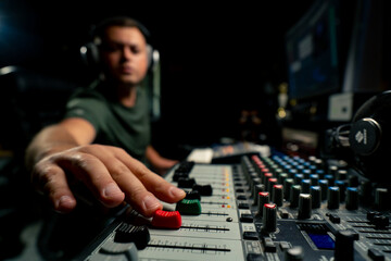 A close-up of a mixing console device used by a man working as professional sound engineer in a...