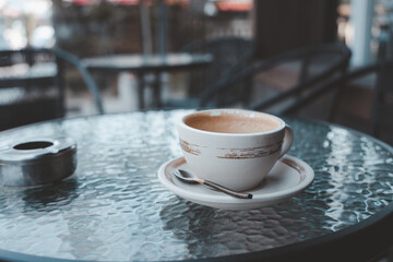 Empty coffee cup after drink with ashtray on outdoor table. Close up