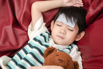 Asian boy She was sick and had a fever reducing patch on her forehead. She was lying on the bed.