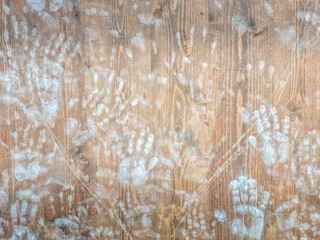 Many handprints on a wooden wall