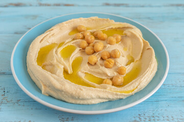 Chickpeas on hummus plate over wooden background.