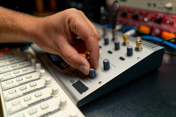 close-up shot of the male hand of a sound engineer switching settings on mixing console for...