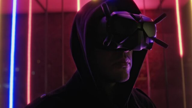 Hooded man in futuristic cyber glasses, portrait with colorful neon illumination, virtual reality, cyberpunk cosplay concept, augmented vision, future style