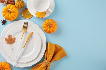 Arrange a Thanksgiving table that's truly memorable. Top view photo of plates, cutlery, cup, napkin, colorful pumpkins, orange, fallen leaves, anise, cinnamon on light blue background with advert area