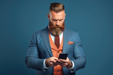 A professional-looking man with a beard wearing a suit, holding a cell phone. This image can be used to depict a businessman, entrepreneur, or professional making a phone call or using technology.
