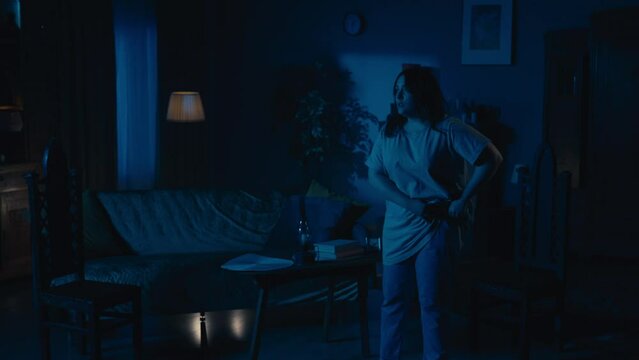 Zoom in video capturing a young woman going around her apartment, noticing paranormal activity, flashing lights in the room. She is calling somebody to get help.