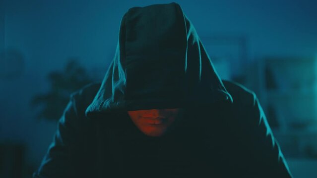 Hooded hacker trading sensitive information on black market in a dark room