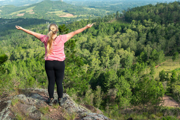 Naklejka na ściany i meble back of female hiker enjoying the view from the mountain top in the forest