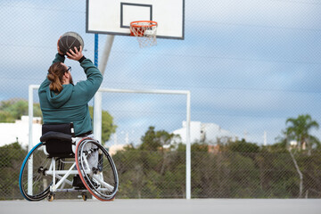 player in wheelchair throwing ball to practice shot in open basketball court