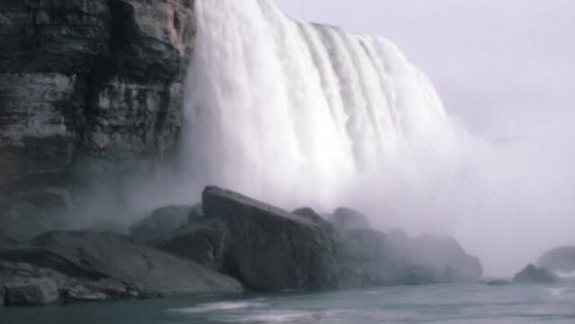 Niagara Falls comes to life in this historic 1970s footage, offering a mesmerizing close-up view from its base. Witness the astounding water volume and towering spray clouds in this awe-inspiring
