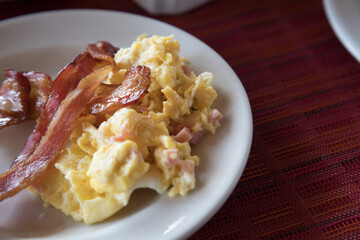 Bacong and scrambled eggs on white plate breakfast food